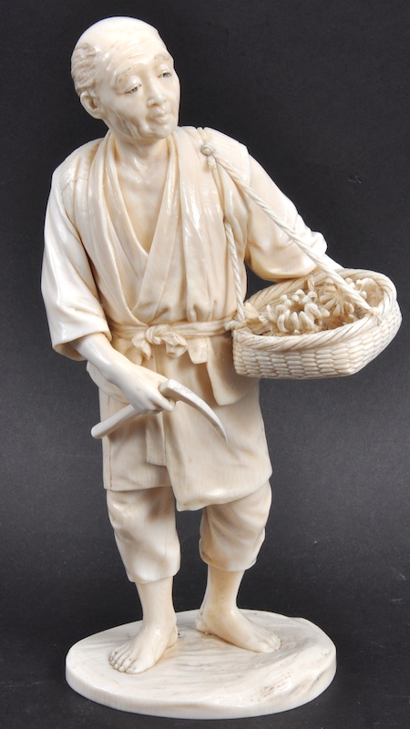 A LATE 19TH CENTURY JAPANESE MEIJI PERIOD IVORY OKIMONO modelled holding a harvest within a