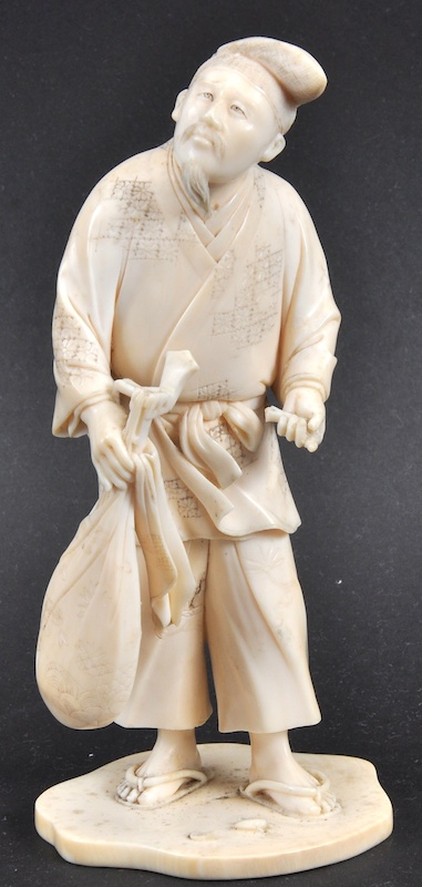 A LATE 19TH CENTURY JAPANESE MEIJI PERIOD IVORY OKIMONO depicting a male holding an instrument.