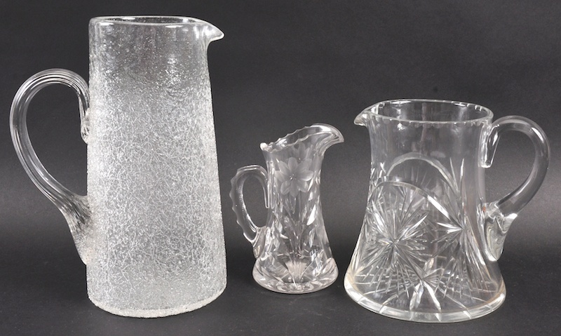 A FROSTED GLASS JUG AND TWO CUT GLASS JUGS, 9.25ins, 6.5ins and 5ins high.