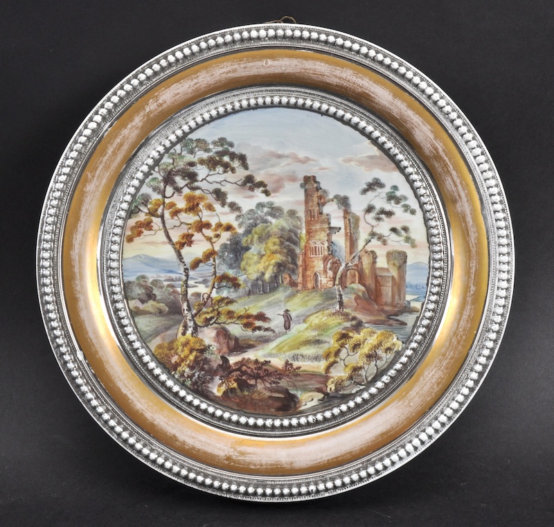 A 19TH CENTURY ENGLISH PORCELAIN PLAQUE painted with landscapes. 10ins diameter.