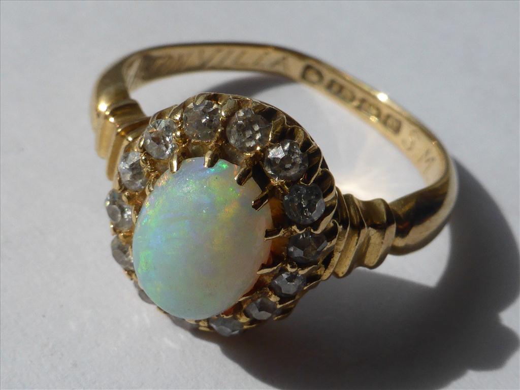 CABOCHON OPAL SET WITHIN A RING OF DIAMONDS ON AN 18CT YELLOW GOLD BANDPostage Cost (basic) : £15