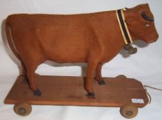 Pre-war standing cow, felt covered on wooden frame with amber eyes on wooden pull along wheel base