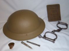 WWII style helmet, WWI signalling book, trench art penny in the form of a cap, pr handcuffs &