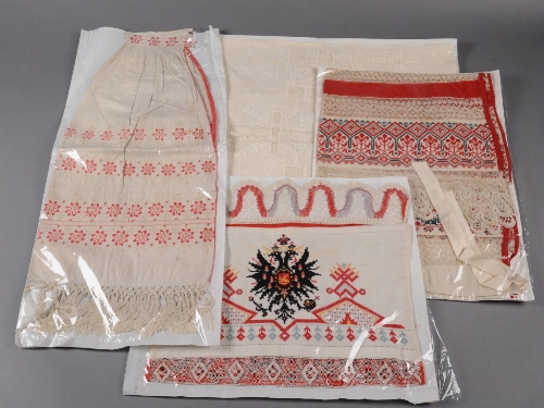 A Russian apron with bands of bobbin lace and red and black cross stitch with bobbin lace edging,