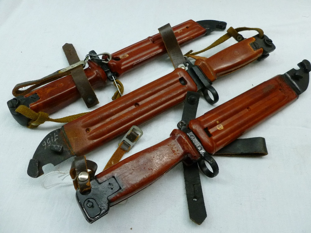 Three AKM (AK47) rifle bayonets with cast brown handles and scabbards, blade length 14cm.