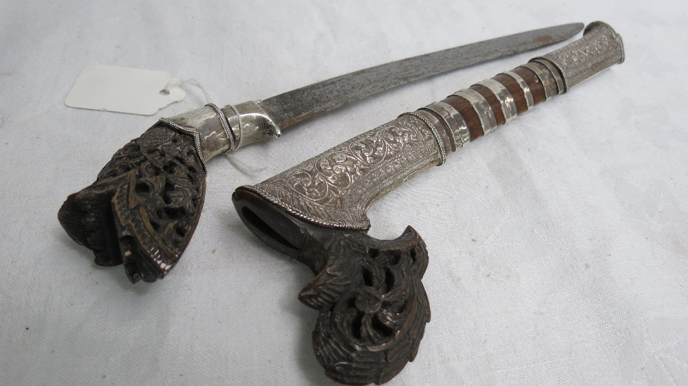 An Oriental dagger with high quality silver fittings and finely carved woodwork, blade 23cm.