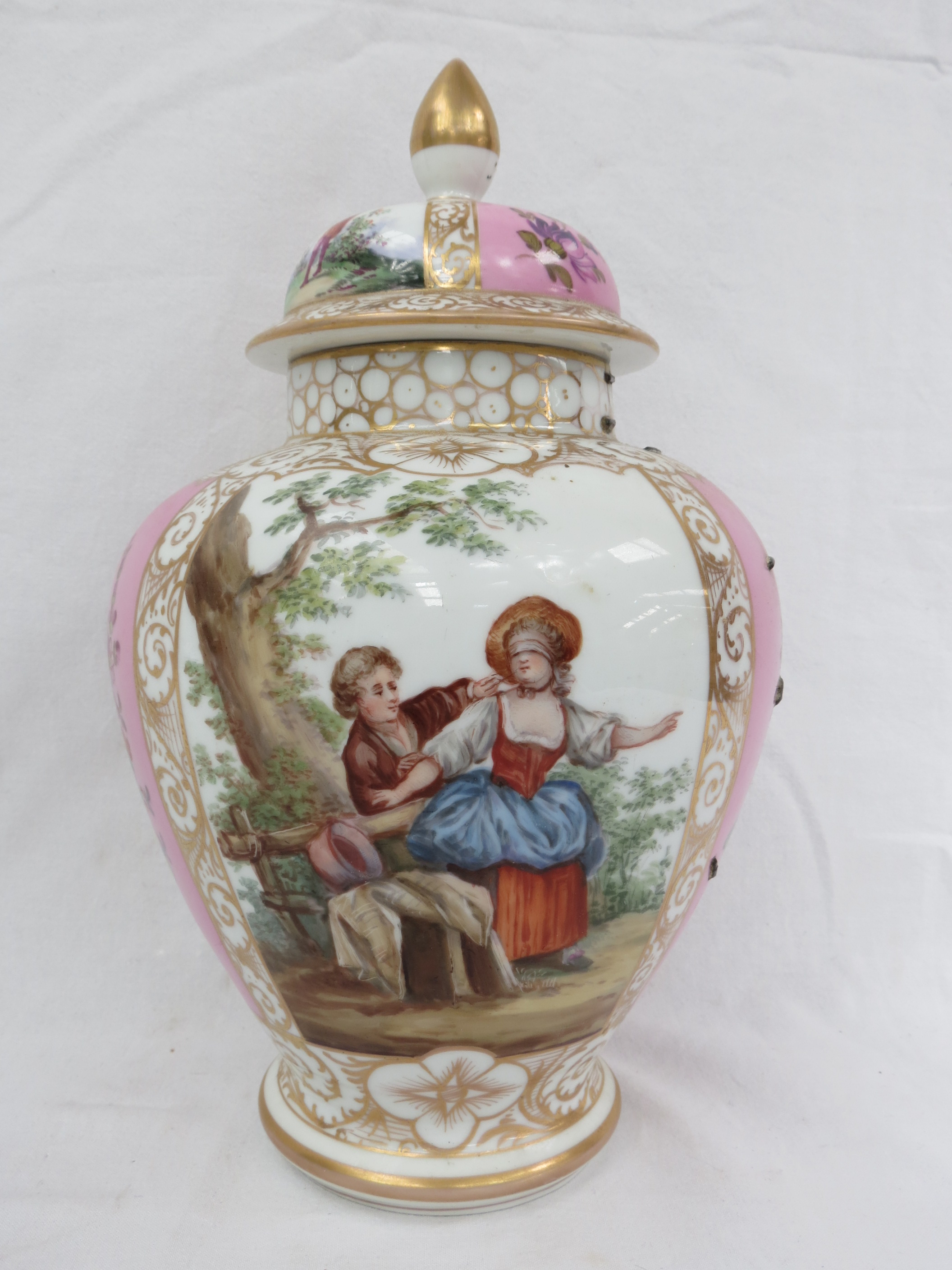 An early 20thC lidded vase of baluster form, decorated in panels of rustic figures and panels of