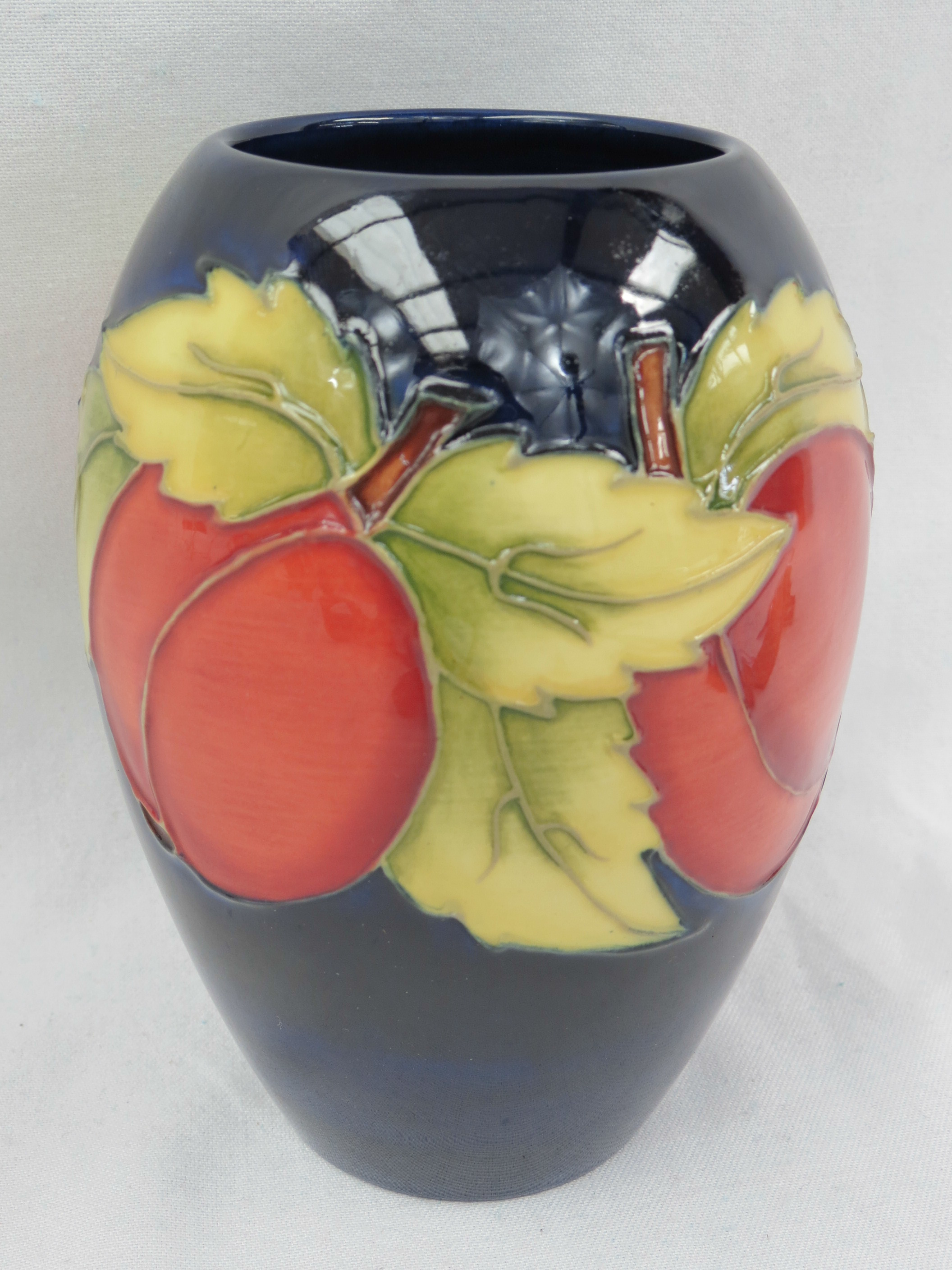 A Moorcroft vase of ovoid form, decorated with plums on a blue ground. 14cm high
