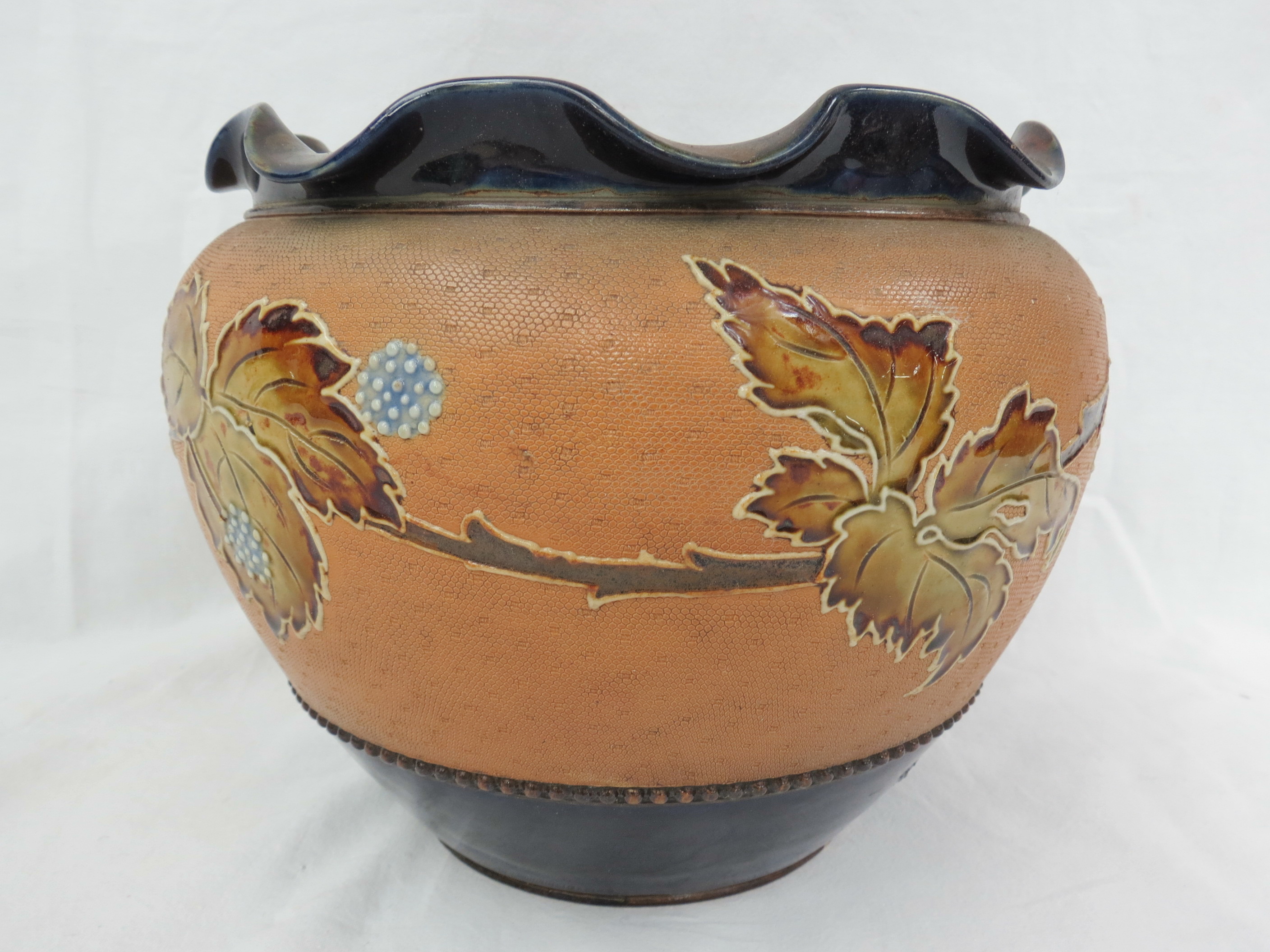 A Royal Doulton stoneware jardiniere decorated with a band of foliage and berries on a tapered