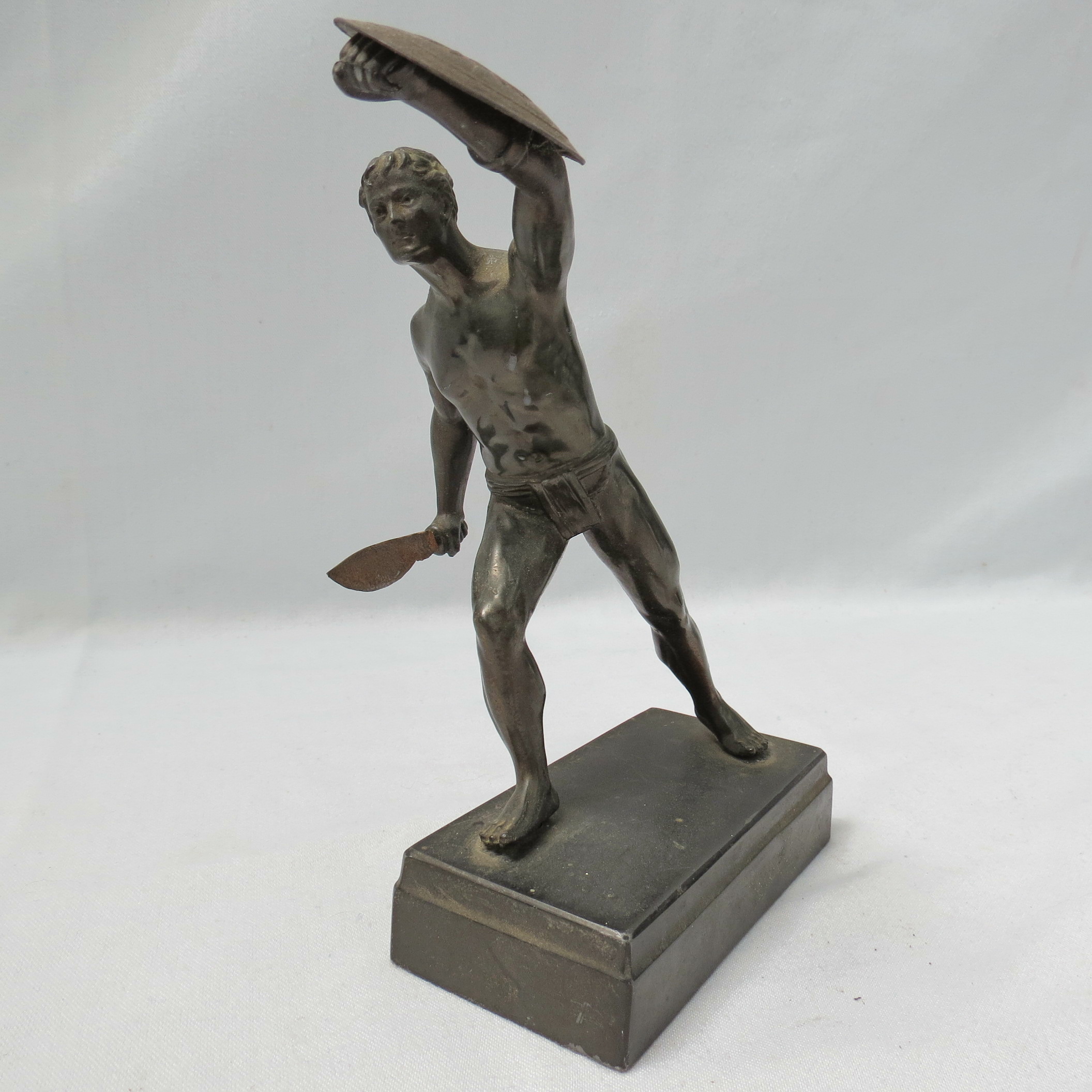 A bronzed metal figure of a gladiator with sword and shield, on a rectangular base, 17cm high