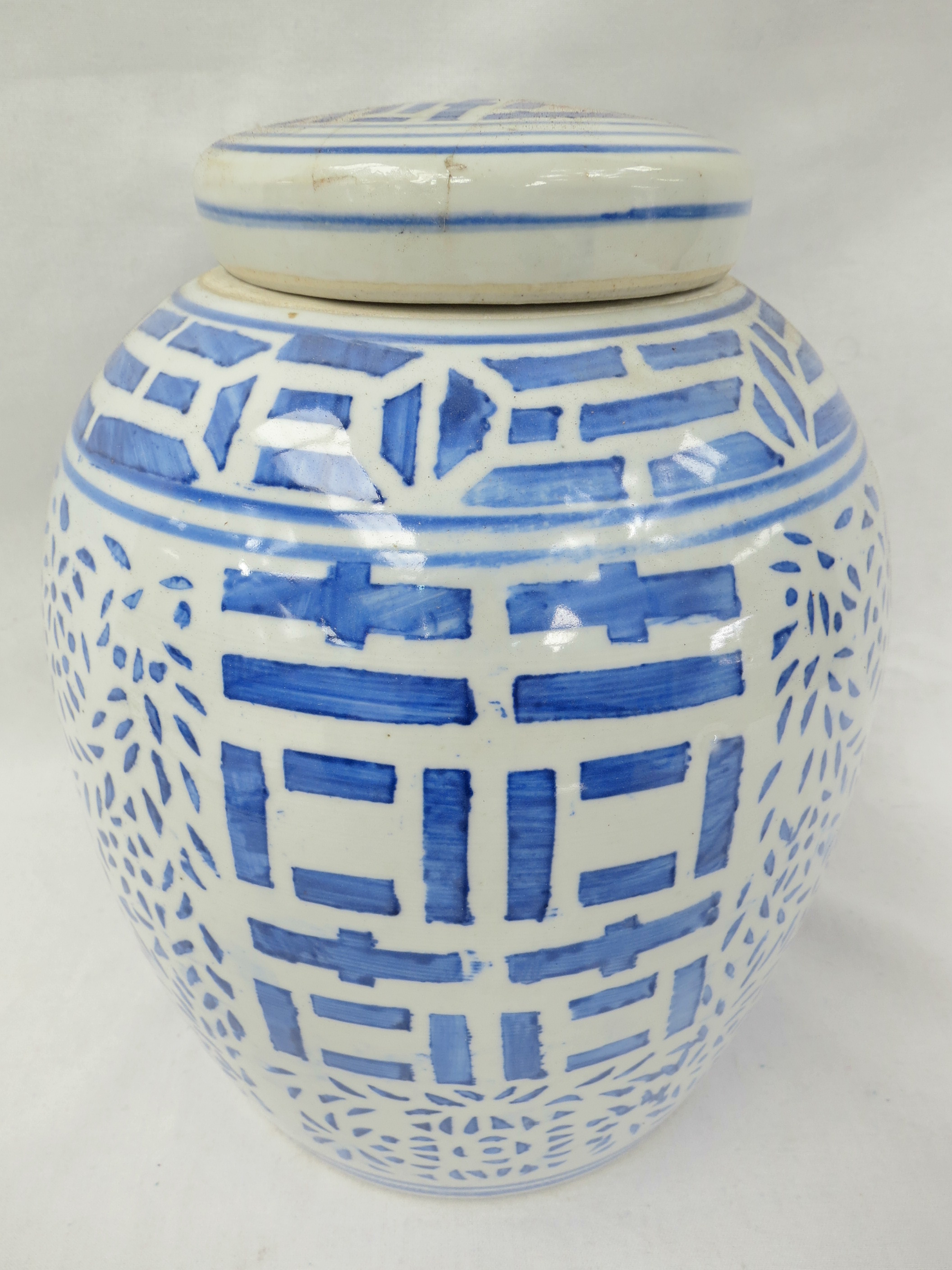 A large 20thC blue and white lidded ginger jar, decorated with a leaf pattern and stylised character