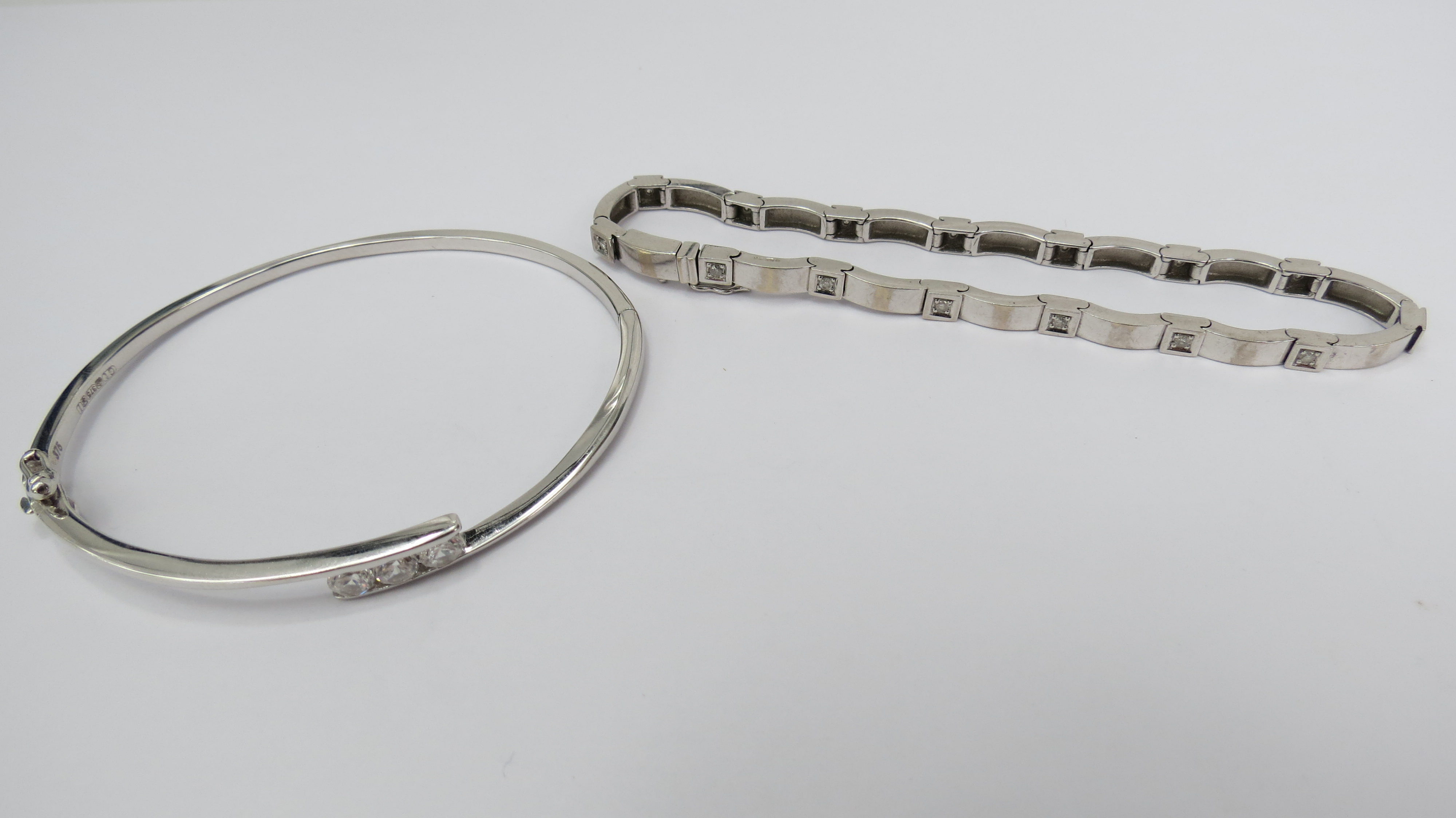 A solid white gold bangle set with three white stones, 9ct, also an articulated bangle set with