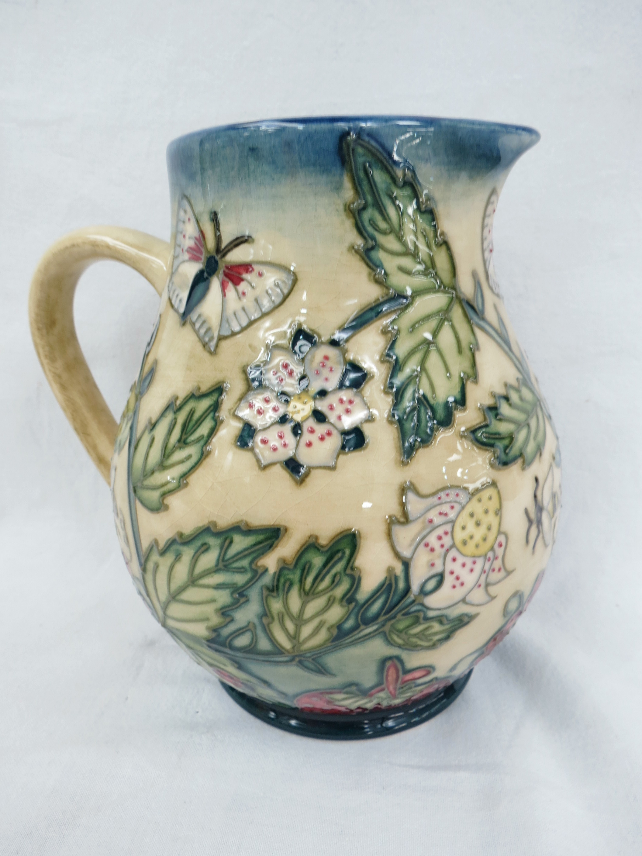 A Moorcroft jug with fruit garden design. 15cm high.