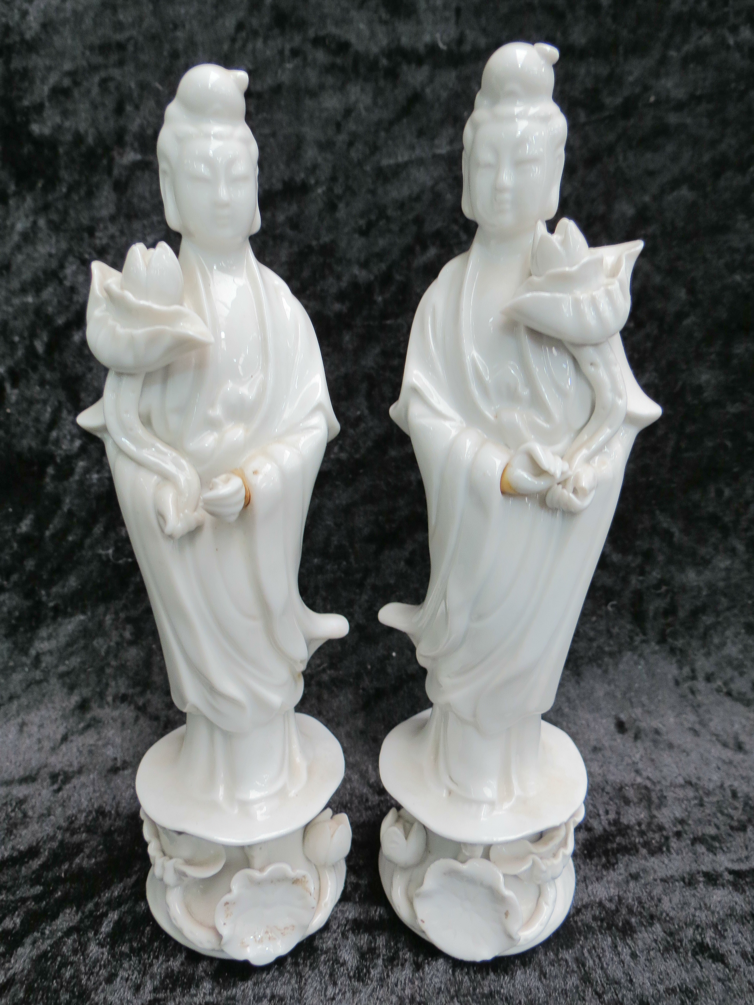 A pair of Blanc de Chine Chinese porcelain figurines in blanc de chine, each holds a lotus and