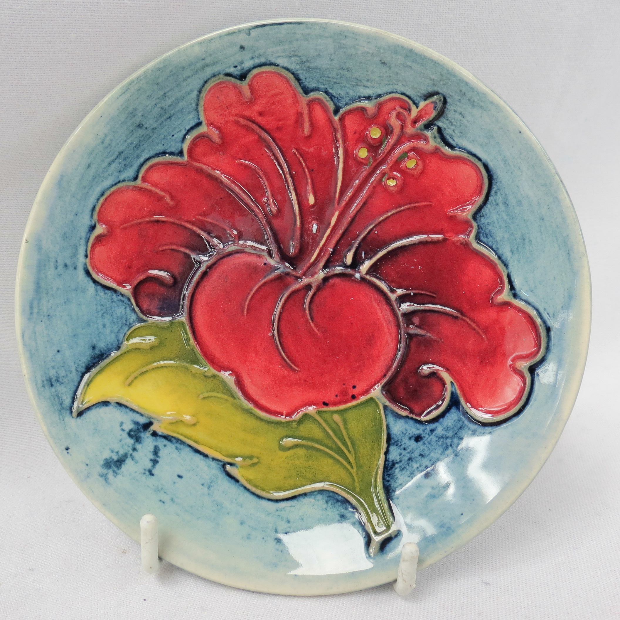 A Walter Moorcroft small dish, of hibiscus pattern on a smoky blue ground. 12cm dia