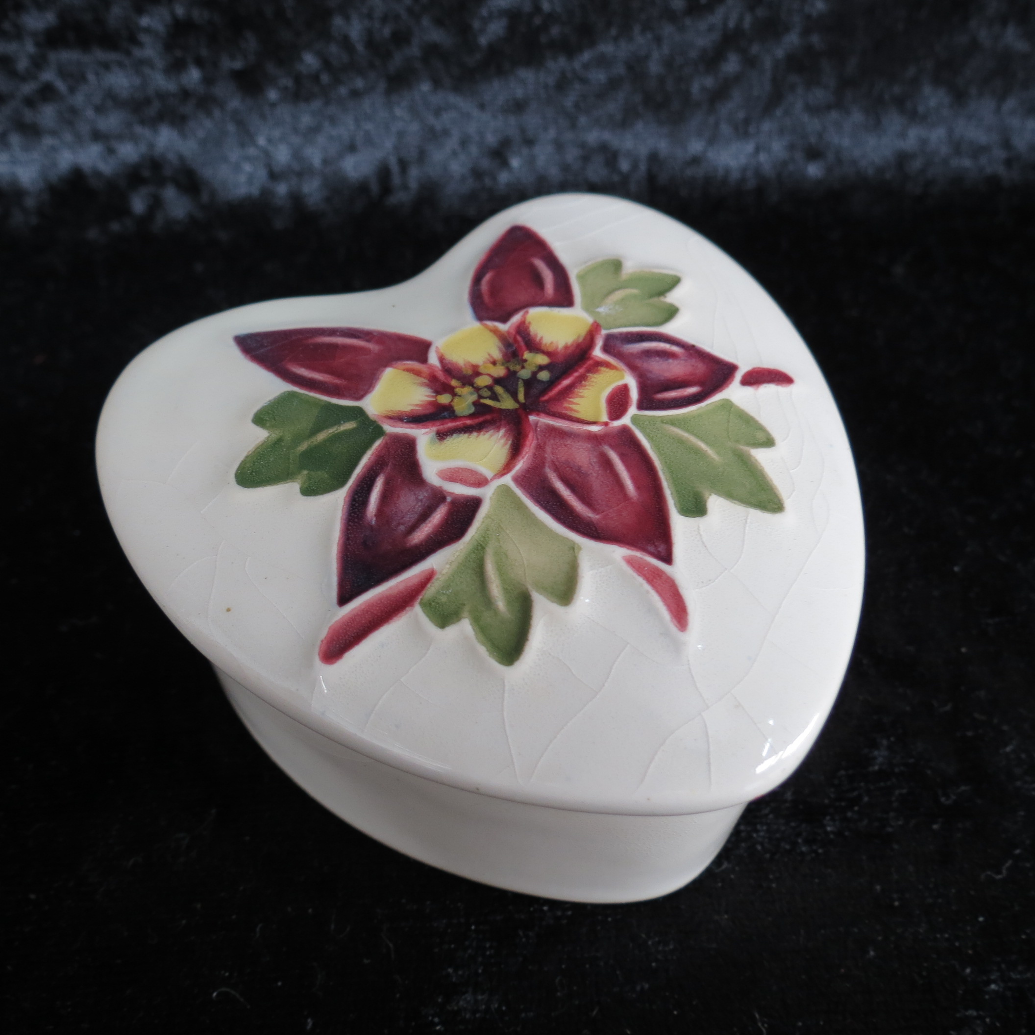 A Moorcroft heart shaped box, decorated  with columbine on a cream ground. 7cm wide.