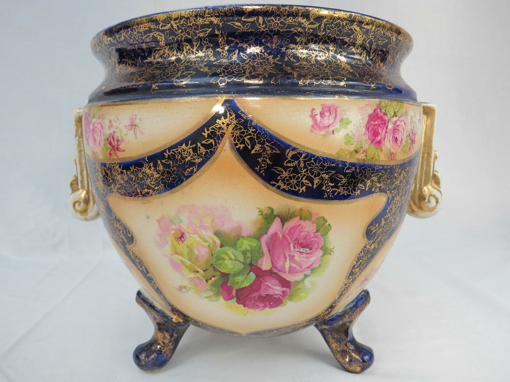 A three-footed jardiniere having rose decoration on a blue ground with gilded details, 10" high.