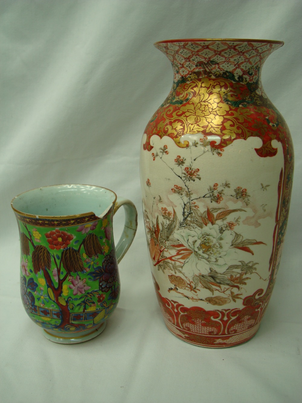 An 18thC green ground floral decorated oriental large mug raised over footed base.  Part gilded. AF.