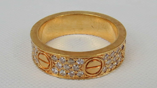 A band of gold triple row of small diamonds separated by screw head pattern panels. Stamped 750