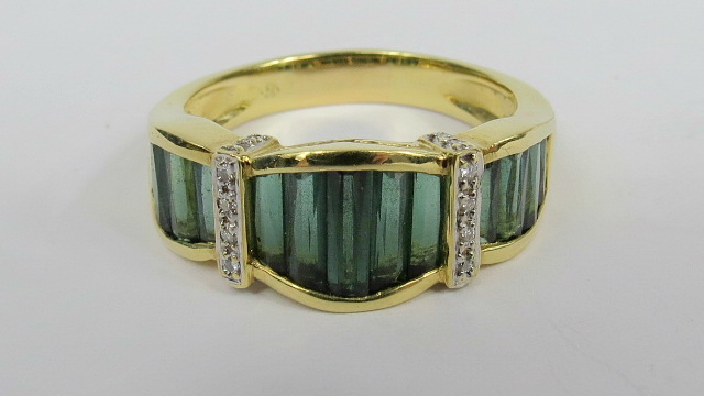 A tourmaline and diamond dress ring, three panels of mixed cut baguette style green tourmalines