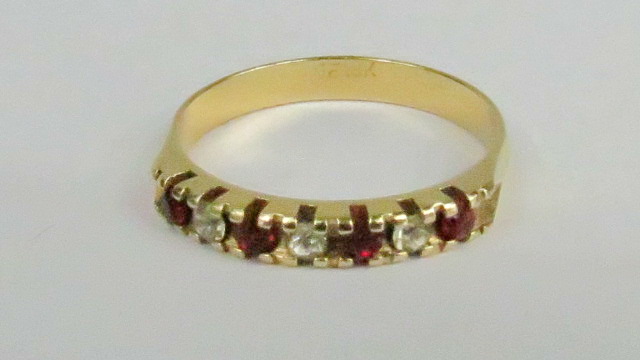 A half eternity ring with red/white stones, indistinct mark on shank.