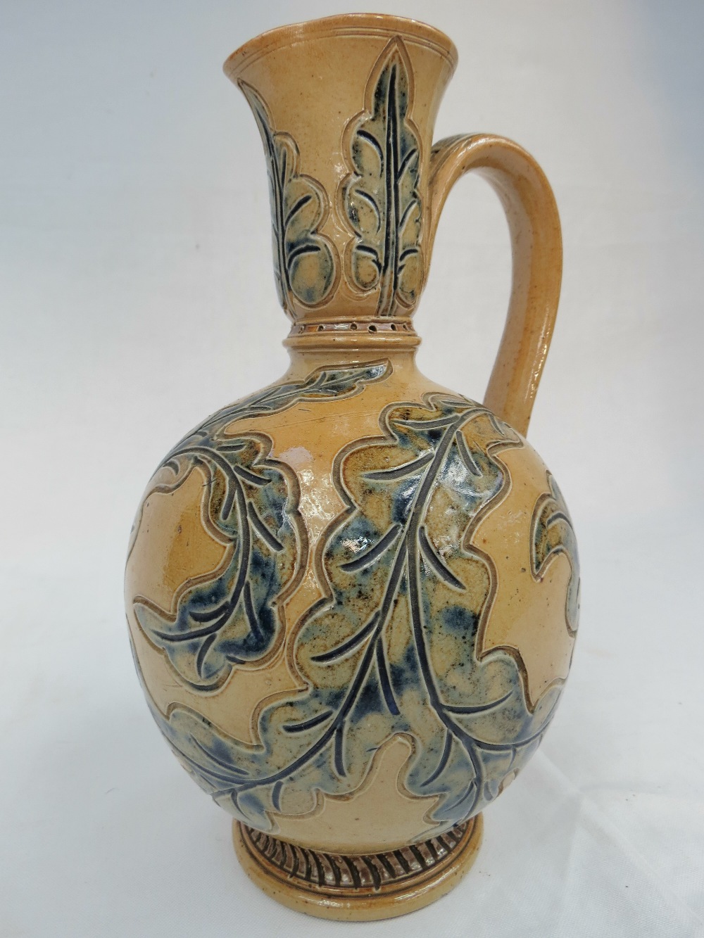 A Doulton Lambeth ewer designed by Frank Butler, biscuit colour with leaf design, 9".