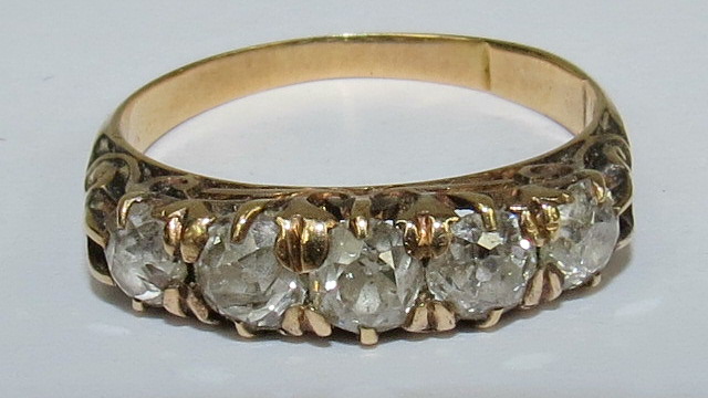 A carved head five stone ring set with old cut diamonds, yellow precious metal mount.