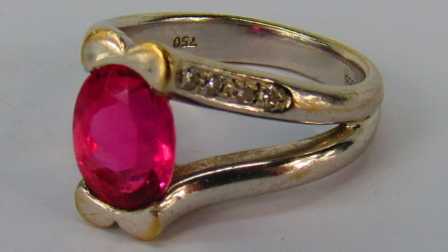 An oval pink tourmaline in split setting, one line of each side set with four single cut diamonds,