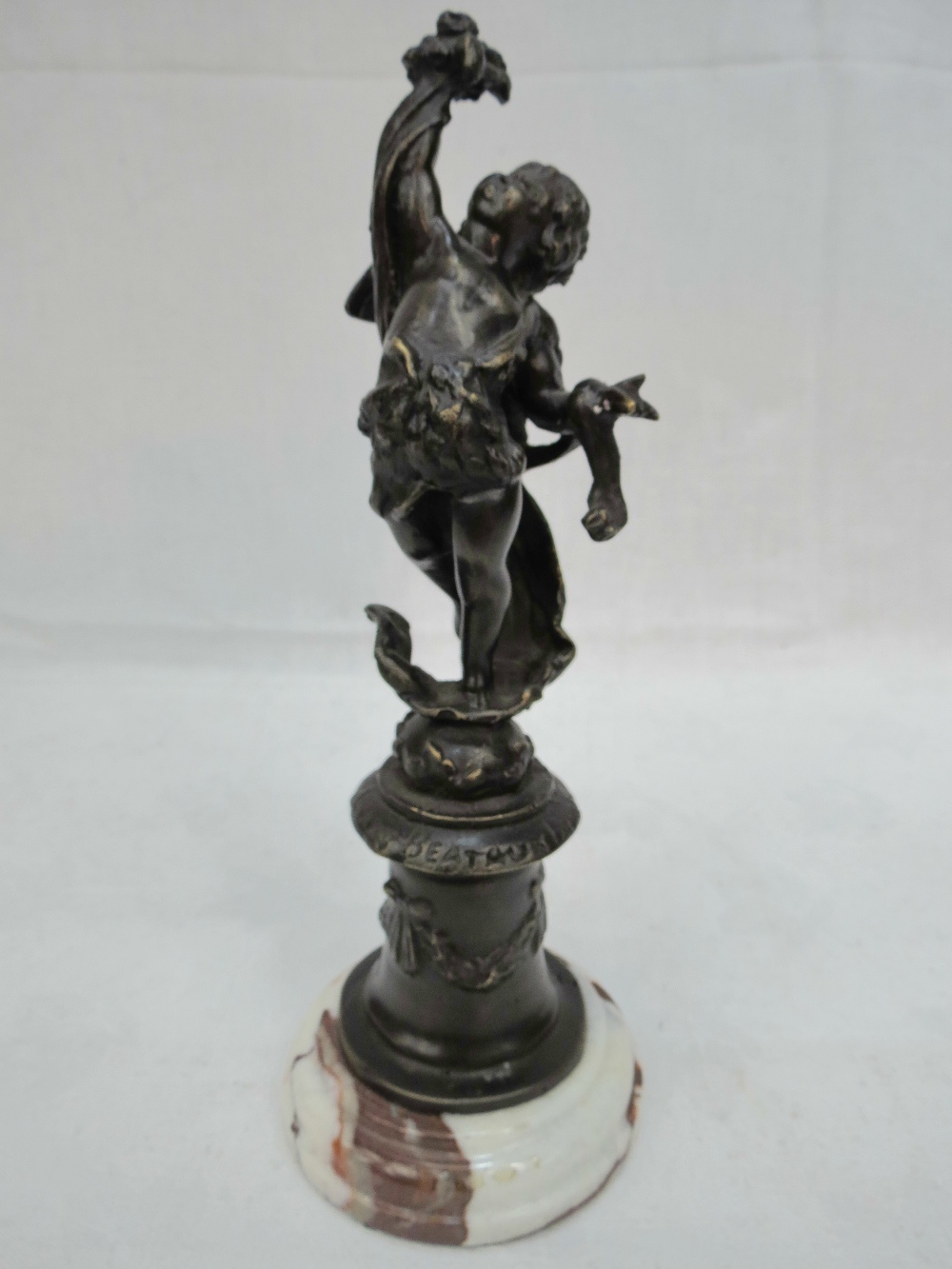 A bronze figure of a cherub on a marble base.