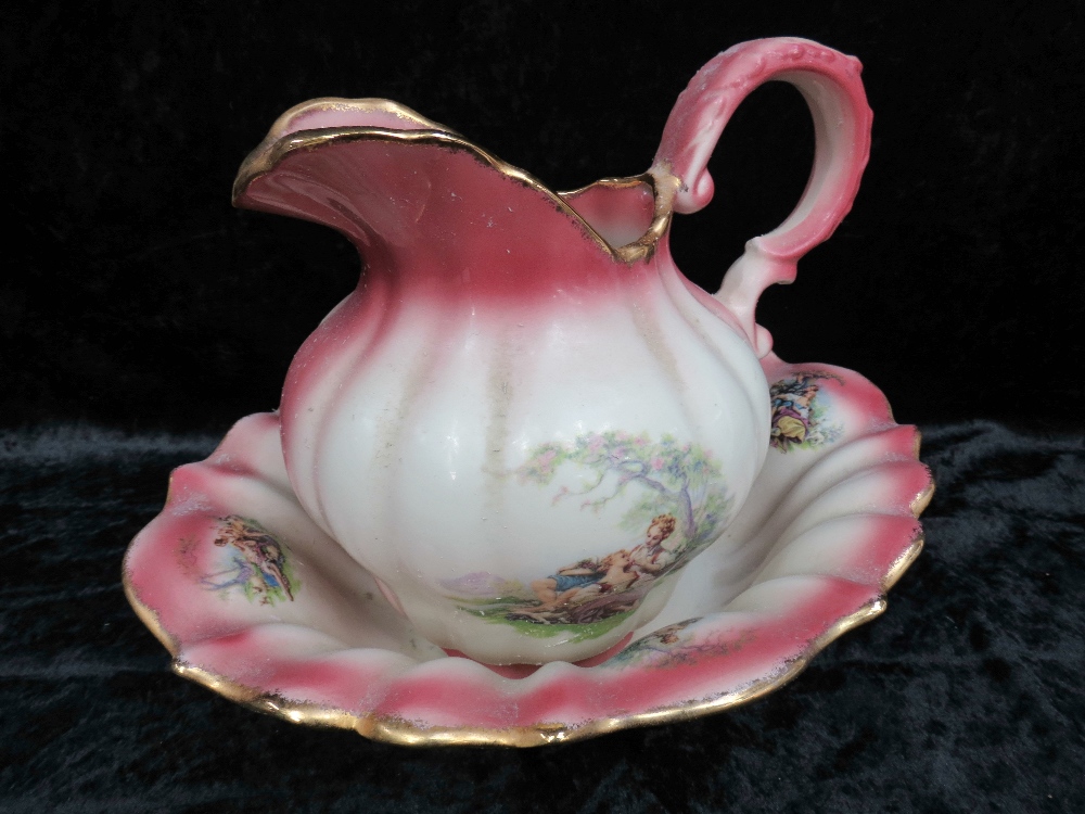 A small Staffordshire wash basin and ewer decorated with romantic vignettes and having gilded rim.