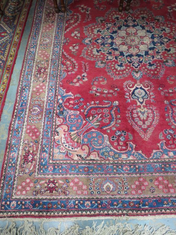 A traditional hand-knotted rug in floral design on red ground, 285x193cm.