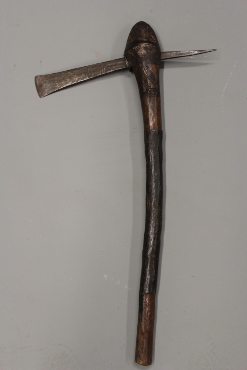 A late 19th Century African axe, the shallow elongated head incised with geometric designs, the wood