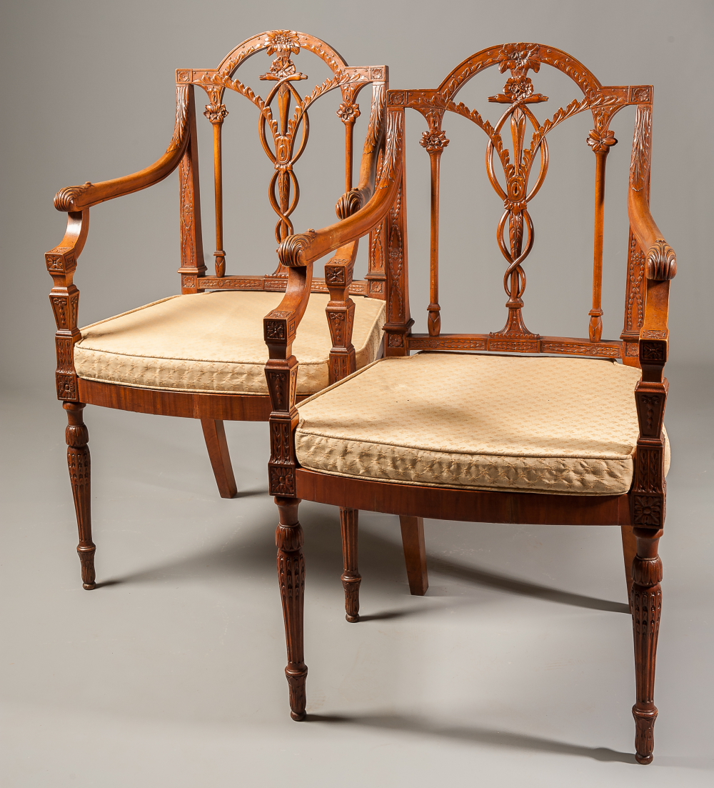 A pair of carved fruitwood armchairs in Neo-Classical style, with foliate and swag motifs to arms