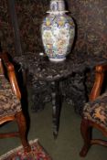 An antique Eastern occasional table, with deep carved decoration, on folding stand.