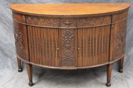 An Edwardian carved mahogany demi-lune cabinet in Neoclassical style, with tambour drawers and