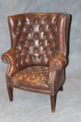A George I style barrel back armchair, with deep button leather upholstery, on plain square