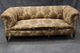 An early 20th Century small Chesterfield sofa, on short square section tapering legs, the brass