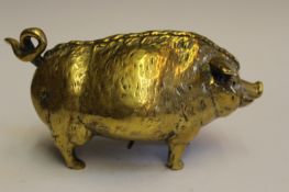 A brass wind up table bell in the form of a corpulent pig, with inset glass eyes, with wind up