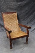 A Colonial carved teak planter’s armchair, with caned seat and back, and adjustable supports.