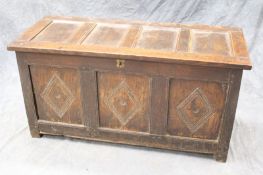 An 18th Century oak coffer, the triple panel top above conforming panel front with chip carved