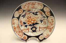 A Japanese Imari barber’s bowl, decorated with a vase of blossoms on a veranda, the border with