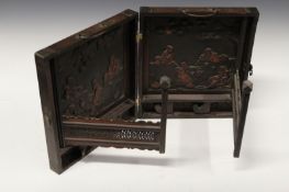 A Chinese carved two part folding small cabinet, each interior panel carved with sages and