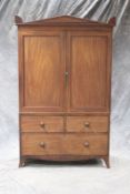 A Regency mahogany clothes press, with carved pediment above panelled doors, two short drawers above