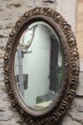 A large oval wall mirror, with carved giltwood and gesso frame, 100cm high.