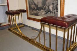A brass club fender, the button leather upholstered seats on brass pole supports.