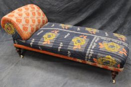 A Victorian day bed, the scroll end with broad seat upholstered in quilted Indian rali linen, on