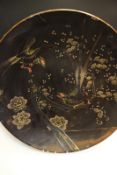 A large Japanese lacquer pottery charger, the upper decorated with black, gilt and red exotic