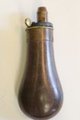 A small copper pistol flask, the pear shaped body retaining traces of lacquered finish, brass top