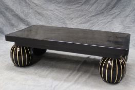 An Art Deco style ebonised coffee table, on inlaid ball feet, 106cm wide.