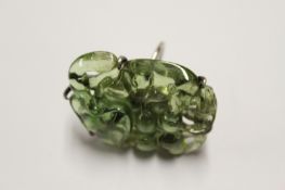 A cut green rock crystal ring in the form of an animal eating berries amidst leaves.